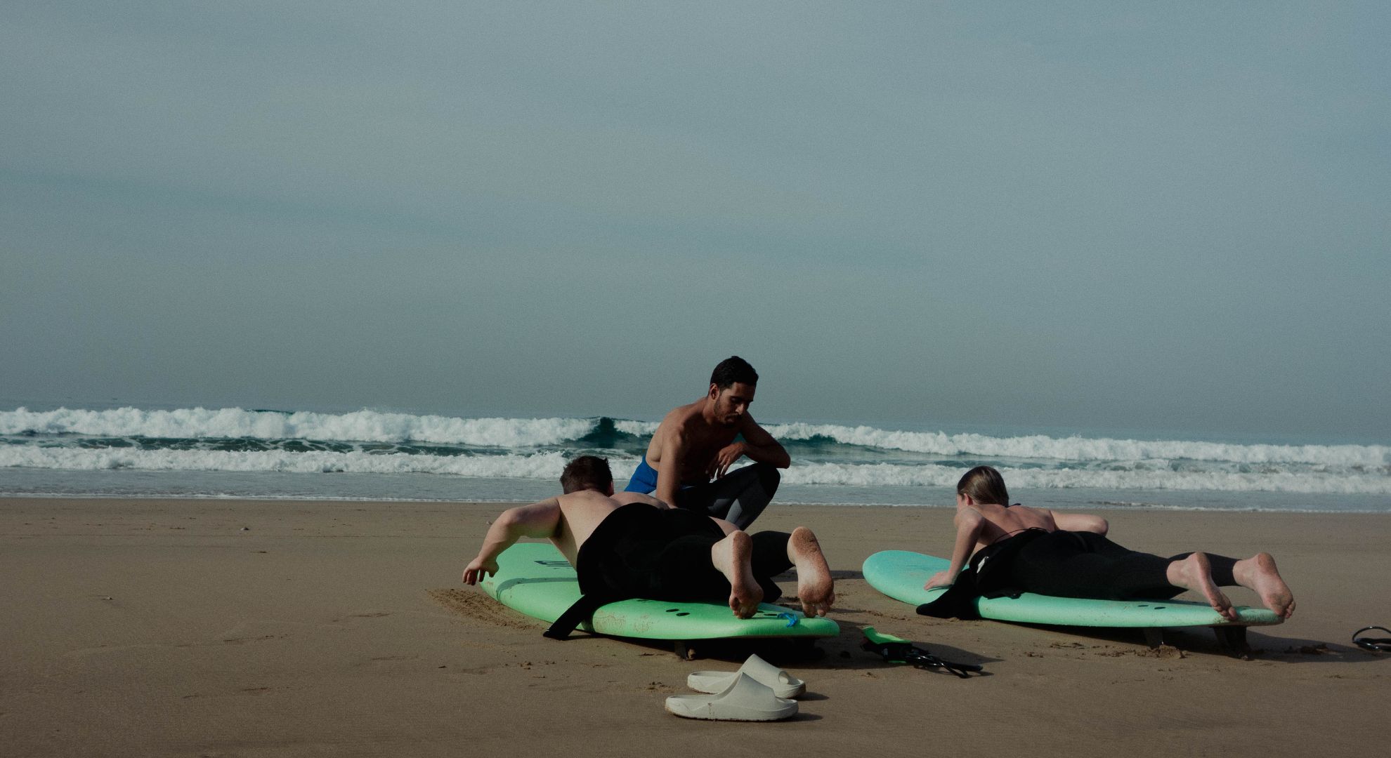 Surf instructor teaching a beginner on the sand